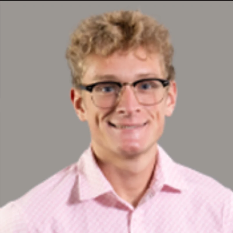 Logann Tuttle wearing glasses and a pink collared shirt.